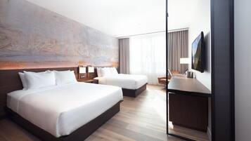 Ein modernes Hotelzimmer mit zwei Betten, einem Schreibtisch und einem großen Kunstwerk an der Wand.