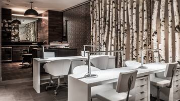 Un salón moderno con un escritorio y sillas blancos, un espejo y una pared con diseño.