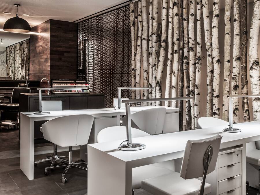 Un salón moderno con un escritorio y sillas blancos, un espejo y una pared con diseño.