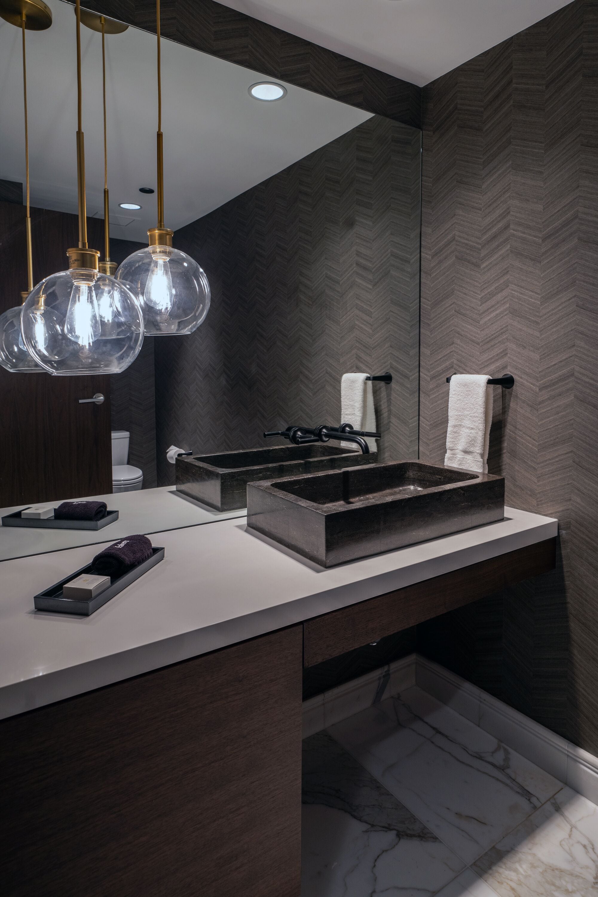 Un bagno moderno con un grande specchio, un lavabo rettangolare e luci a sospensione.