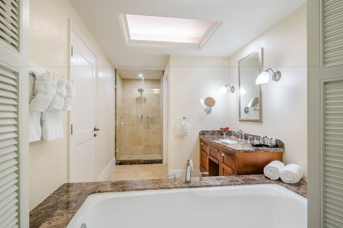A modern bathroom with a large bathtub, a walk-in shower, and a vanity with a mirror and sink.