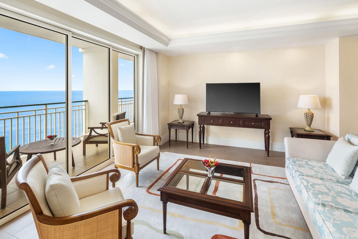 A spacious living room with a large balcony, a flat-screen TV, and comfortable seating.