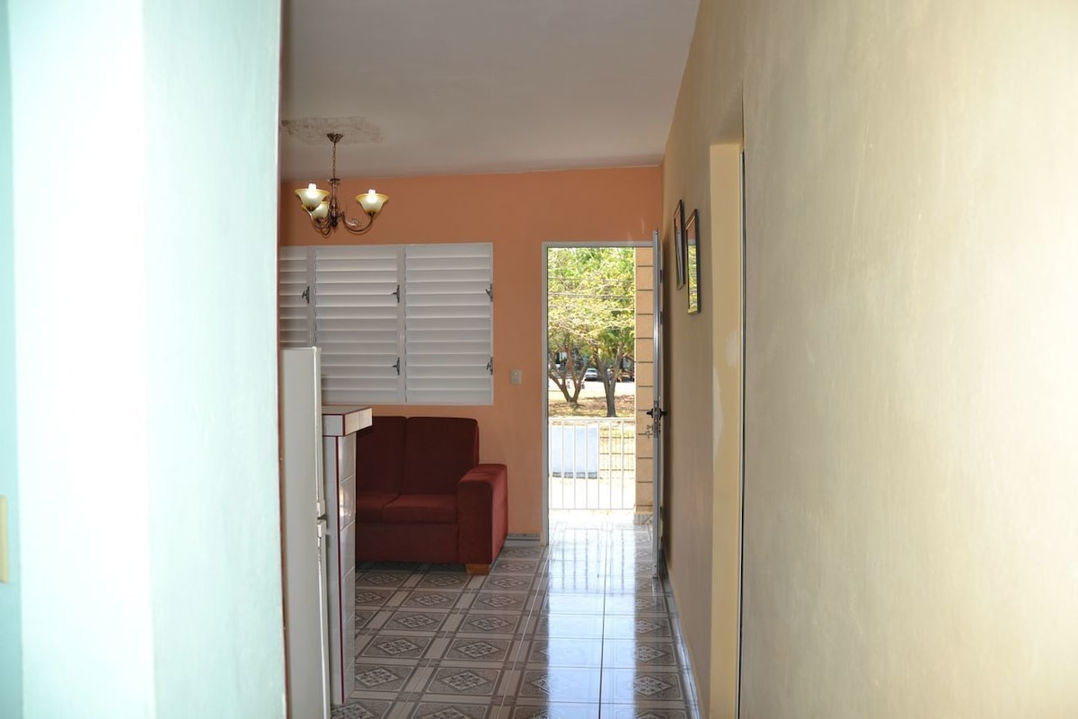 A hallway with a red sofa, a chandelier, and a door leading to an outdoor area.