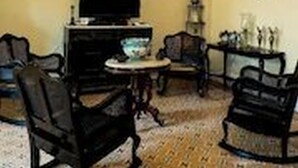A living room with a television, two framed artworks, a chandelier, and a small round table. - Dona Amalia (Cienfuegos)