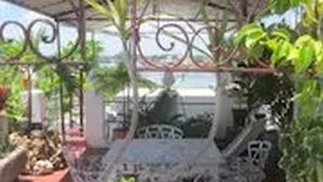An outdoor patio area with a metal table and chairs, surrounded by greenery and a decorative metal fence. - Dona Amalia (Cienfuegos)