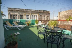 Enjoy panoramic views of the city from this rooftop retreat, featuring a lush green space with lounge seating and a small dining area.