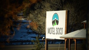 Schild für 'Motel Soco' mit einem Logo, das eine Berglandschaft mit Bäumen zeigt.