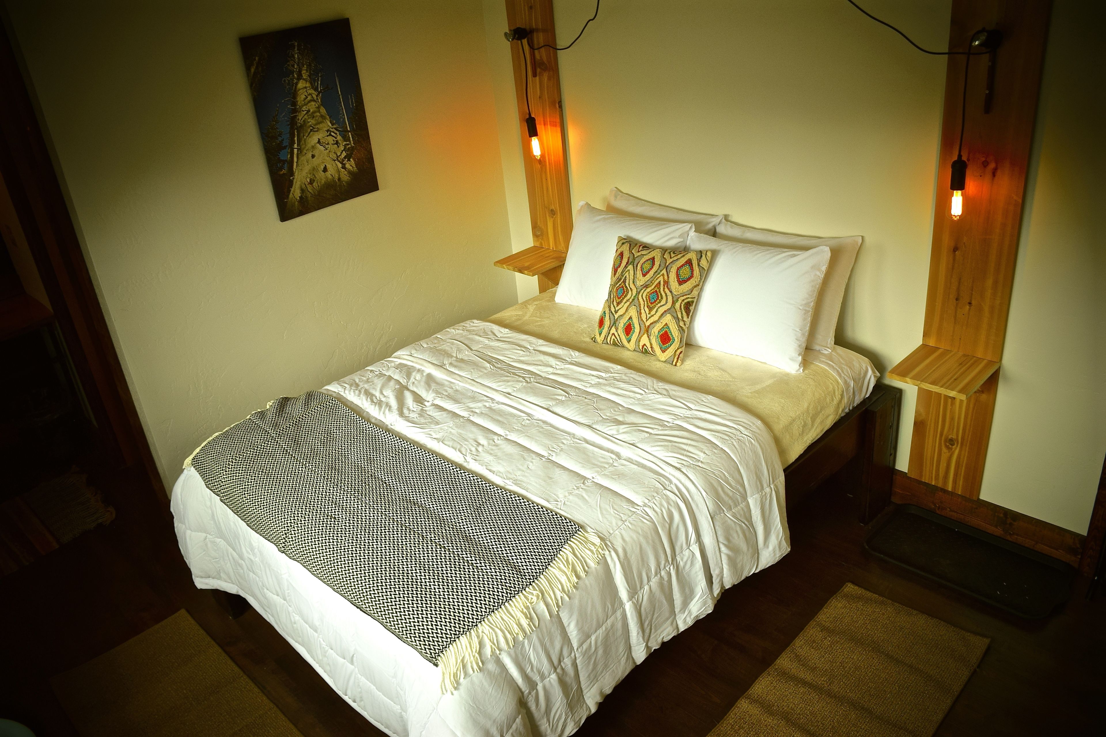 A neatly made bed with a patterned throw, wooden headboard, and bedside lamps.
