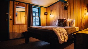 Ein gemütliches Zimmer mit einem Bett, einem Fenster und einer Wandleuchte.