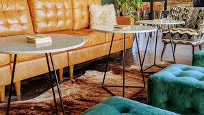 Ein gemütlicher Lounge-Bereich mit einer Ledersofa, einem runden Couchtisch und blaugrünen Ottomanen.