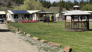Ein Campingplatz mit Holzhütten, einem Pavillon und einem kleinen Gebäude mit Solaranlage.