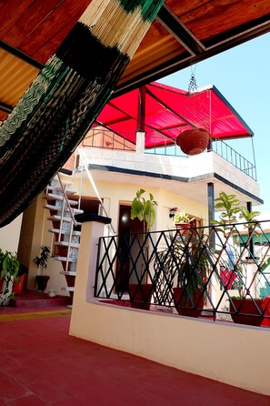 Un bâtiment à deux étages, doté d’un auvent rouge, d’un escalier et de plantes en pot.
