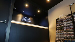 Ein Hotel-Empfangsbereich mit dunkler Wand, einem Schild mit der Aufschrift "HOTEL LIVEDAX" und einer Präsentation von Broschüren.