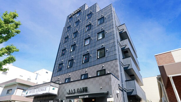 Ein modernes Hotelgebäude mit einem Schild für 'Hotel Livemax' und 'Max Cafe' im Erdgeschoss.