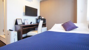 Ein Hotelzimmer mit Bett, Schreibtisch mit Stuhl, Fernseher und Kaffeemaschine.