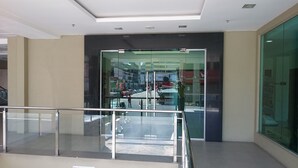 Un intérieur moderne avec une entrée dotée d’une porte en verre, un panneau indiquant qu’il s’agit d’un espace public et un sol carrelé.