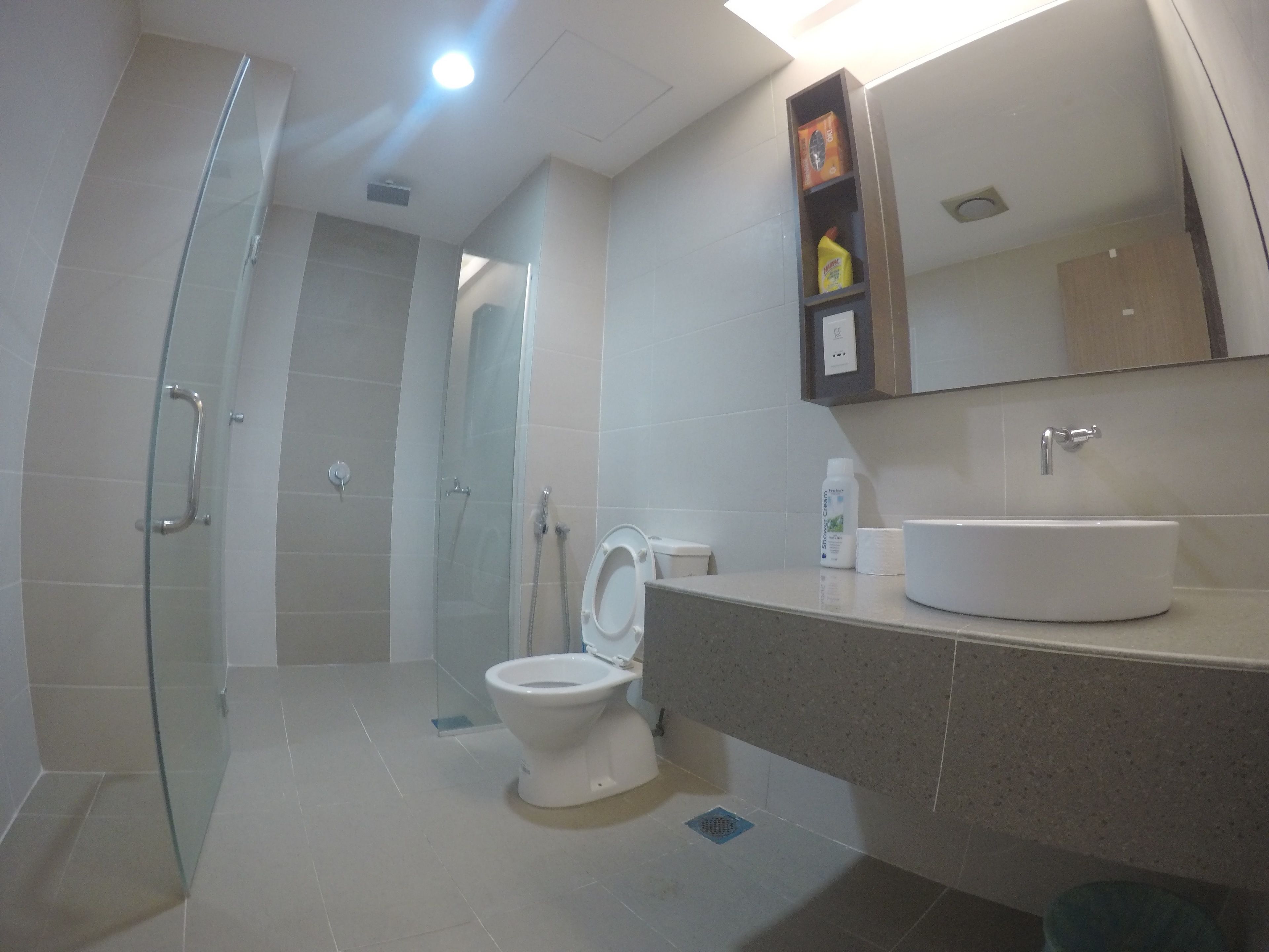 Un baño moderno con cabina de ducha de vidrio, inodoro blanco y encimera de granito con lavabo.
