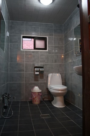 A small bathroom with a toilet, a sink, and a shower.