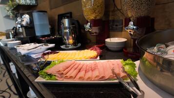 A buffet with various food items, including sliced meats and cheeses, arranged on plates.