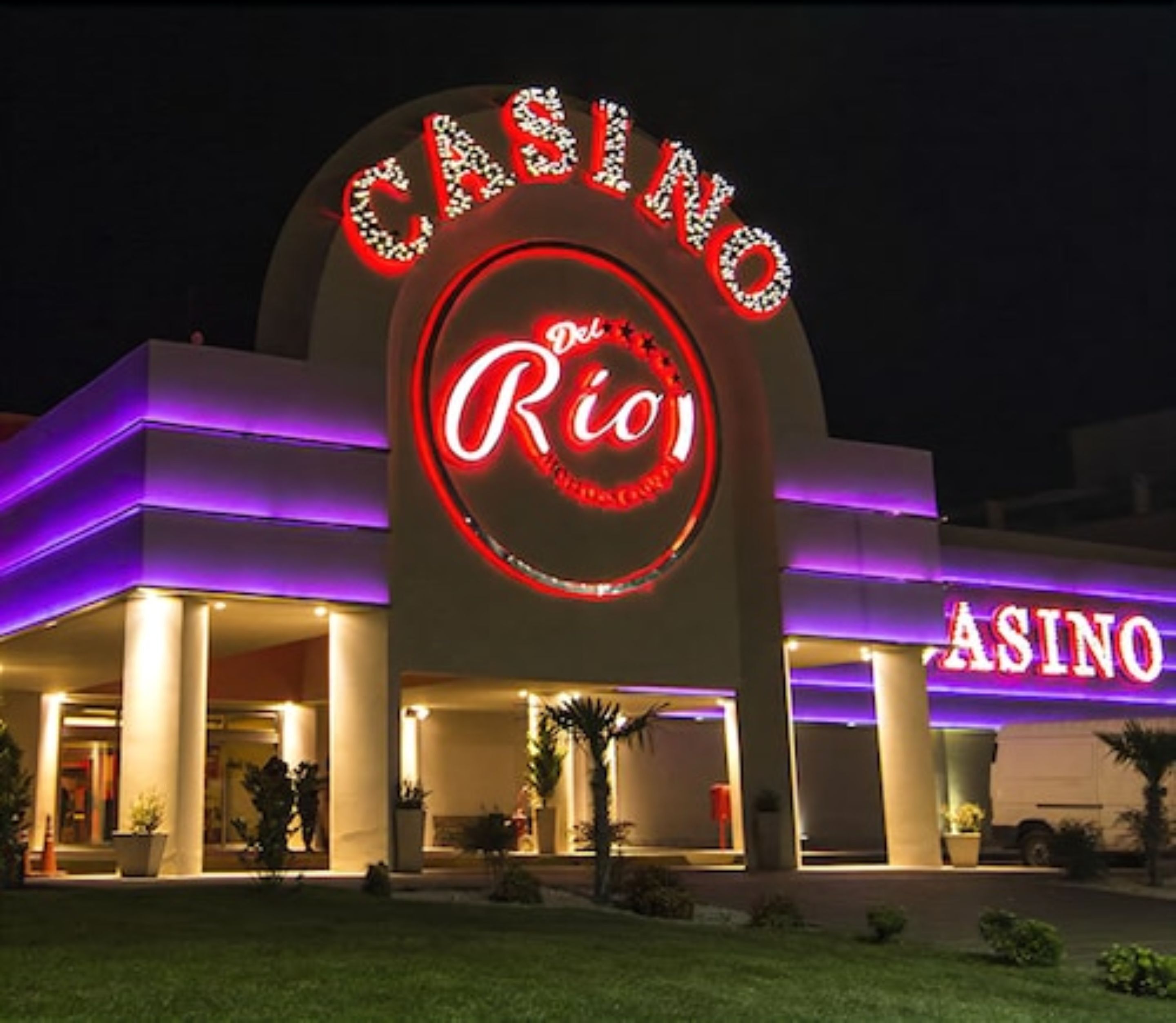 Un edificio de casino con un llamativo letrero de neón que dice "CASINO Rio" y "ASINO".