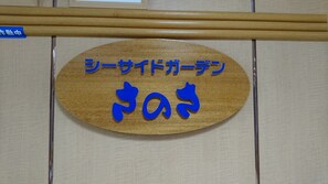 Un letrero de madera con caracteres japoneses y una flecha azul que apunta a la derecha.