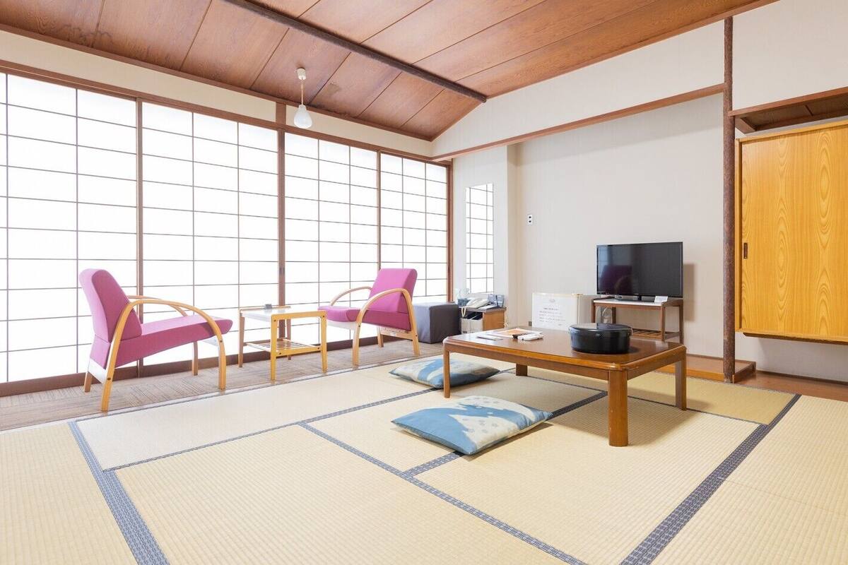 Una habitación tradicional japonesa con suelo de tatami, televisor y armario de madera.