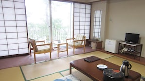 A traditional Japanese-style room with tatami flooring, a low table with a kettle and teapot, and a television on a small table. - Hotel Axia Kushikino (Ichikikushikino)