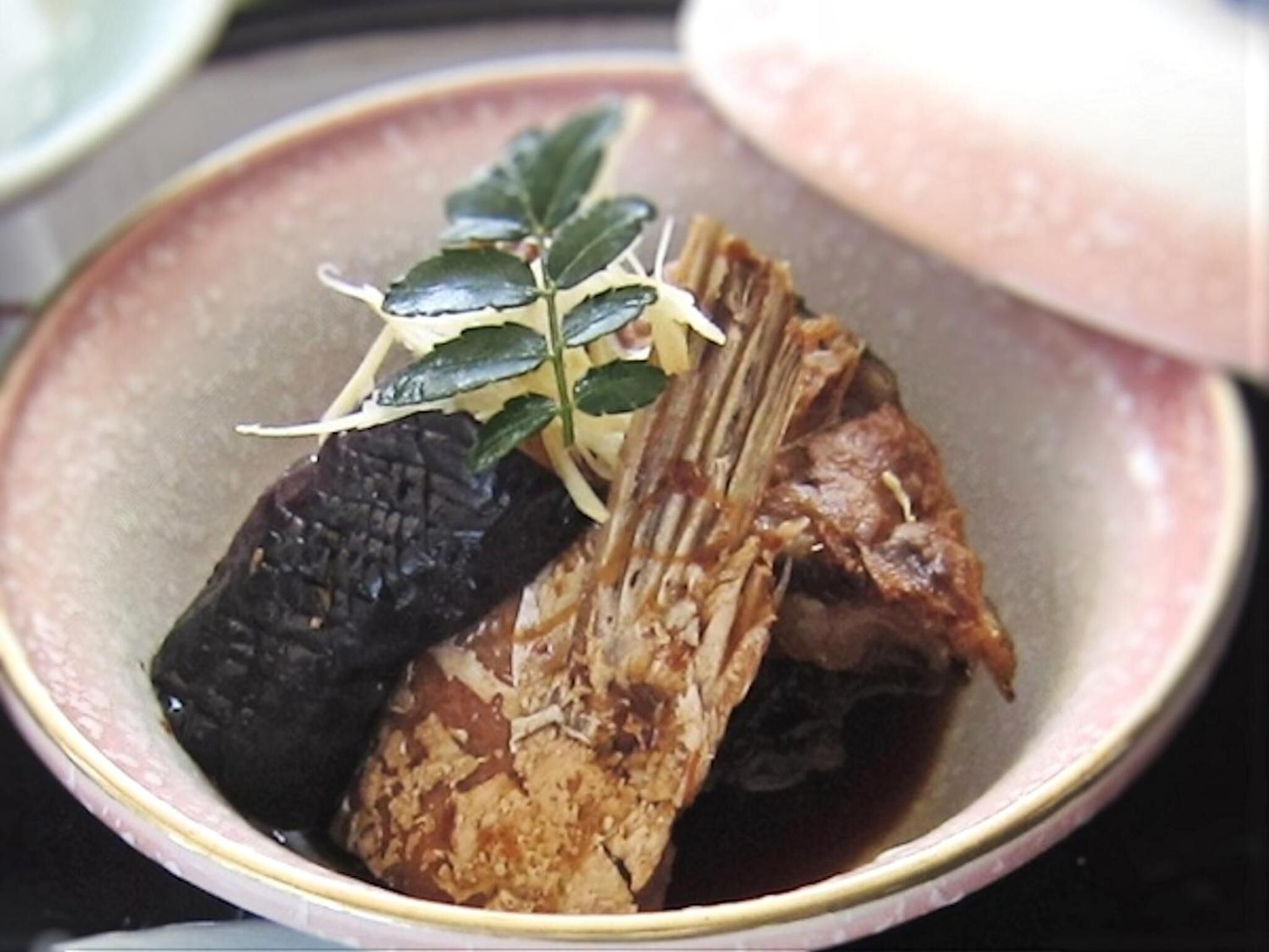 A dish with a dark, textured item and a fork on a pink plate.