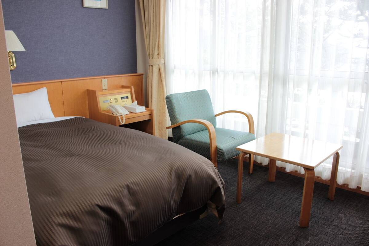Una habitación de hotel con cama, escritorio, silla y teléfono.