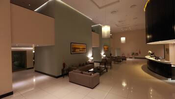A spacious lobby with a reception desk, seating area, and artwork on the walls.