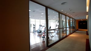 Un gimnasio con equipamiento de ejercicio y ventanas amplias.