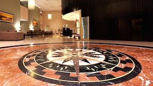 Un vestíbulo con un diseño circular en el suelo, zonas de estar y un mostrador de recepción.