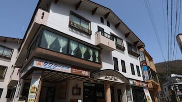 A multi-story building with a cafe and restaurant on the ground floor, a visible sign for a monkey tour, and a clear sky above.