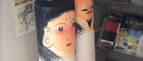 Two cylindrical objects with painted faces, a bulletin board with various papers, and a shelf with magazines.