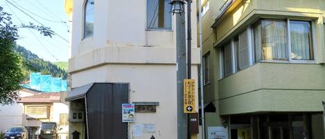 A building with a beige facade, a black awning, and a sign indicating a business.