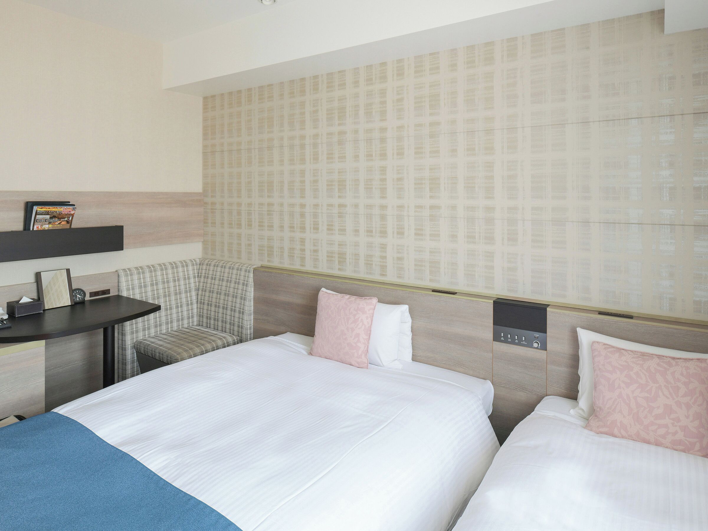 Ein Hotelzimmer mit zwei Betten, einem Schreibtisch und einem Sessel.