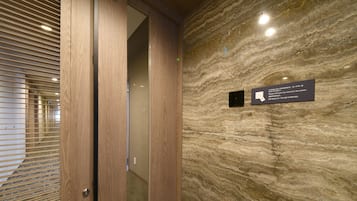 A modern elevator interior with a marble wall and a sign indicating a card reader for room access.