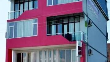 Un hotel de varios pisos con una fachada distintiva roja y blanca, ventanas amplias y un balcón en el piso superior.