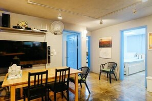 Un espace de vie compact comprenant un coin repas, un téléviseur et un ventilateur.
