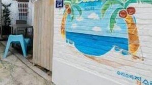 Un bâtiment dont l’un des murs est décoré d’une fresque représentant une scène de plage.