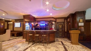 A bar area with a marble floor, wooden bar counter, and stools.