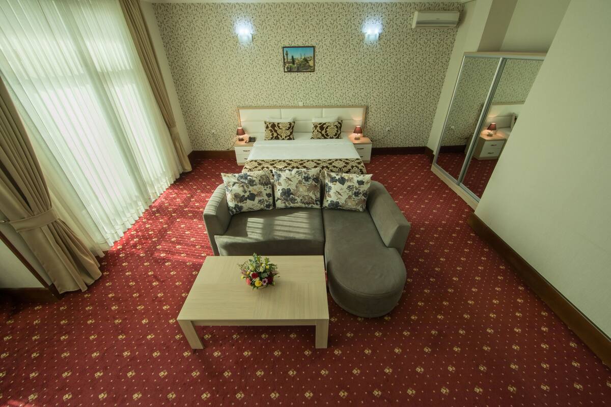 Une chambre d’hôtel avec un lit, un canapé, une table basse et un miroir.