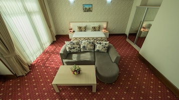 Een hotelkamer met een bed, een slaapbank, een salontafel en een spiegel.