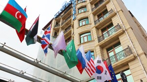 A hotel building with multiple flags, including those of Azerbaijan, the UK, Russia, and the EU.