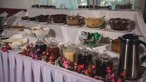 A buffet table with various food items and beverages, including bowls of cereal, nuts, and a coffee pot.