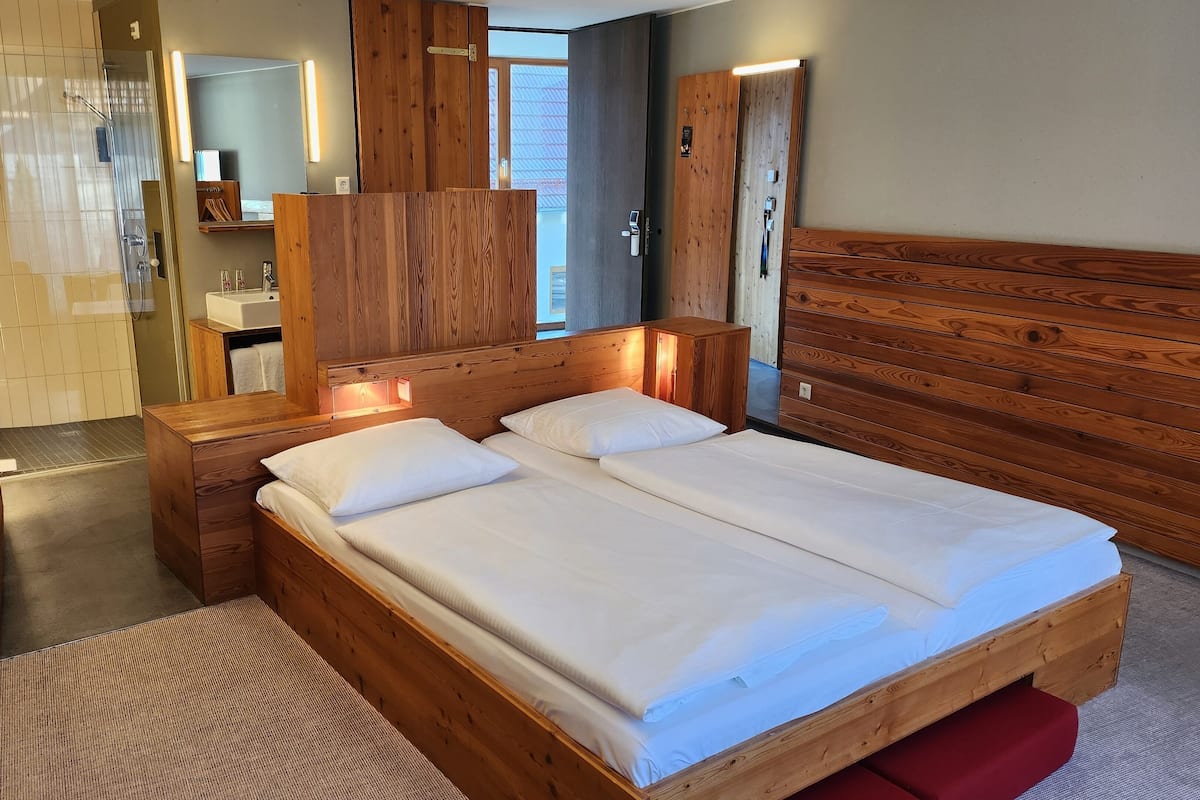 Une pièce en bois avec un lit, une armoire en bois, un miroir et une salle de bain avec une douche.
