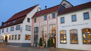 A row of traditional European buildings with large windows and a red-tiled roof. - Speidel's Brau Manufaktur (Hohenstein)