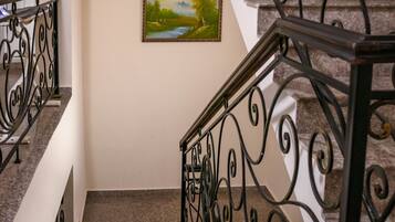 Una escalera con barandales negros ornamentados y un cuadro de paisaje enmarcado en la pared.