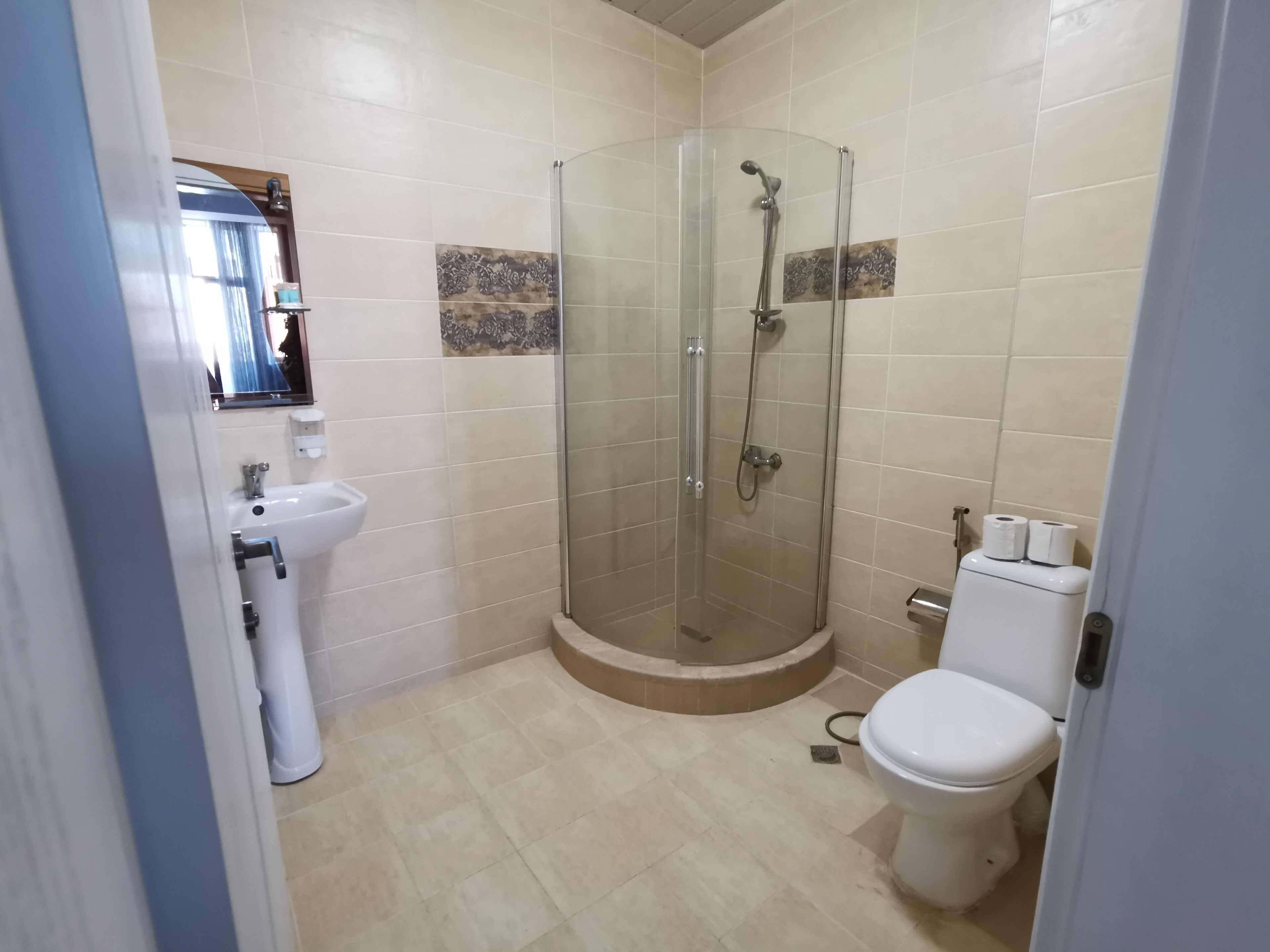 A bathroom with a glass-enclosed shower, a sink, and a toilet.