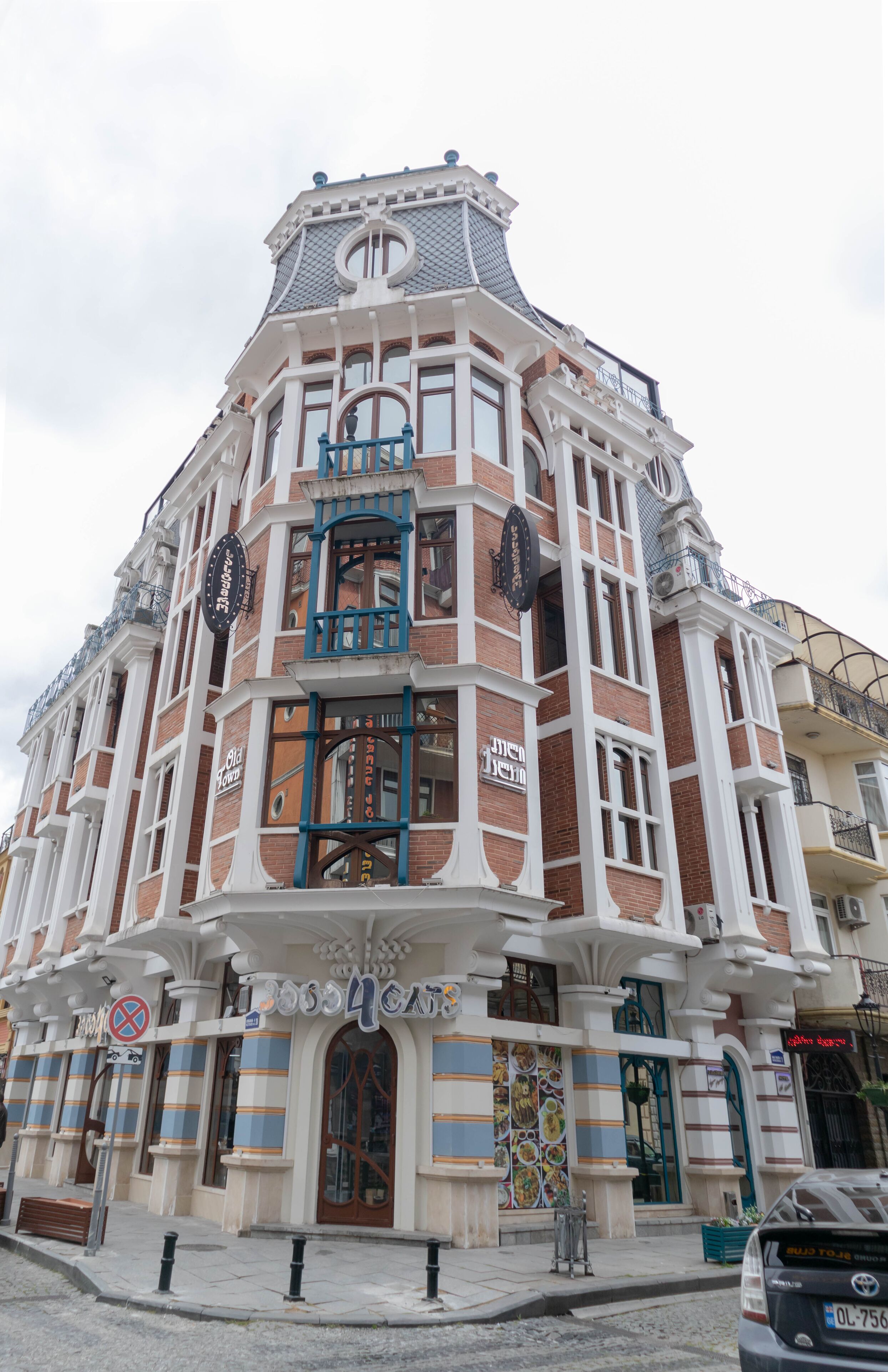 A historic building with a prominent corner entrance, large windows, and a balcony.